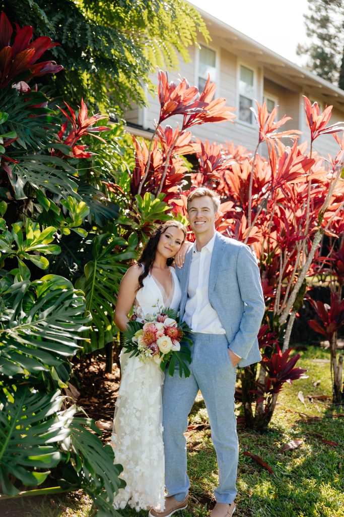 a couple in wedding attire posing in front of lush tropical foliage in Kauai
