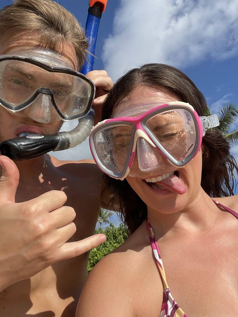 a couple wearing snorkel gear on the beach making goofy faces