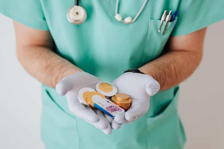 travel nurse wearing hospital uniform and stethoscope, holding out money in their hands, representing travel nurse financial mistakes