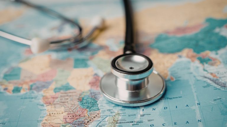a map with a stethoscope laying on it, implying that you can volunteer globally as a humanitarian nurse